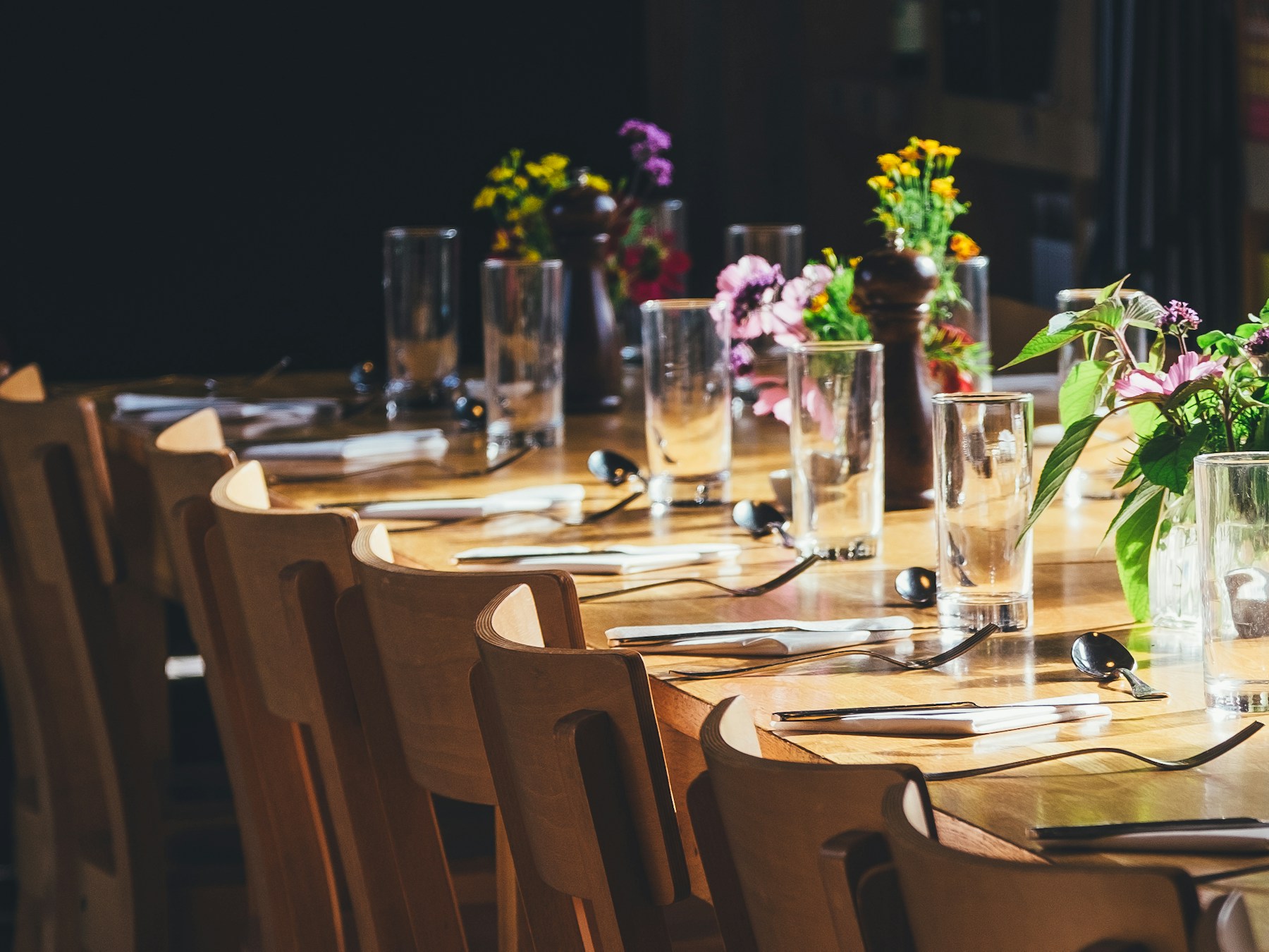 Mesa elegante posta com vasos de flores e taças em luz natural — ambiente típico de um encontro matinal de empresários